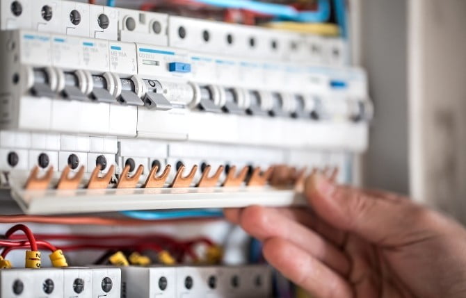 man electrical technician working switchboard with fuses installation connection electrical equipment close up